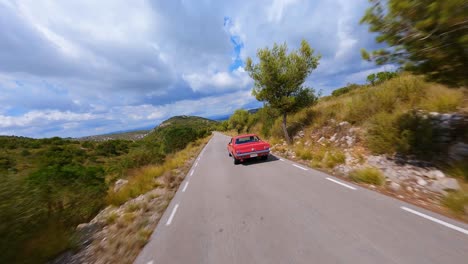 Magnífica-Y-Cinematográfica-Vista-Aérea-De-Un-Clásico-Mustang-Rojo-Conduciendo-A-Través-De-Un-Pintoresco-Paisaje-Montañoso