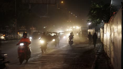 Busy-Traffic-at-Night-in-New-Delhi-India,-motorcycles-and-scooters-passing-by