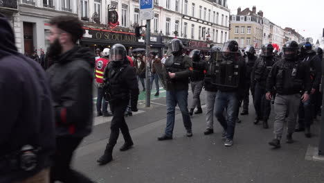 Una-Unidad-De-Policías-Antidisturbios-Vestidos-De-Civil-Que-Portan-Escudos-Y-Cascos-Caminan-Junto-A-Un-Grupo-De-Manifestantes-Durante-La-Huelga-Nacional-Y-Las-Protestas-Por-El-Aumento-De-La-Edad-De-Jubilación.