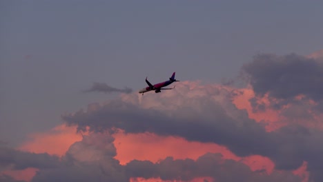 Una-Toma-Cámara-En-Mano-Captura-Un-Avión-De-Wizzair-Aterrizando-En-Split,-Croacia,-Durante-Una-Pintoresca-Puesta-De-Sol-Con-Palmeras-En-Primer-Plano.