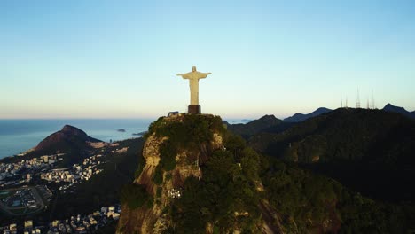 Vista-Aérea-Alrededor-De-La-Estatua-Del-Cristo-Redentor,-Revelando-La-Ciudad-De-Río-De-Janeiro,-Puesta-De-Sol-En-Brasil