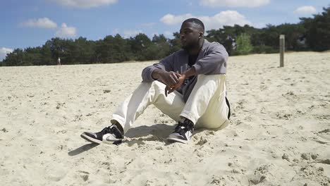 Young-man-sitting-alone-on-a-beach-while-enjoying-the-peaceful-lake-view