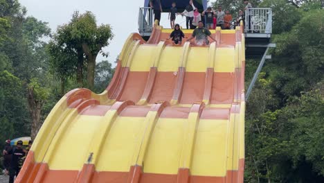 Romantic-couple-enjoying-colorful-water-slide-ride-at-the-waterpark-during-summer-holiday,-water-splashing-moment