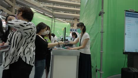 Señora-Recibiendo-Un-Folleto-En-Un-Stand-De-Exposición-Tecnológica