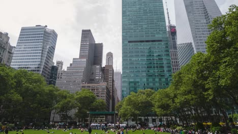 Timelapse-De-Bryant-Park-En-Nueva-York-Durante-El-Día-Con-Gente-Caminando,-Comiendo-Y-Disfrutando-Del-Centro-De-Manhattan,-Con-Rascacielos-Alrededor-Y-Nubes-Pasando