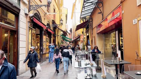 Cámara-Lenta-De-Un-Grupo-De-Personas-Caminando-Por-Las-Tiendas-Y-Cafés-De-Las-Calles-De-Bolonia,-Italia
