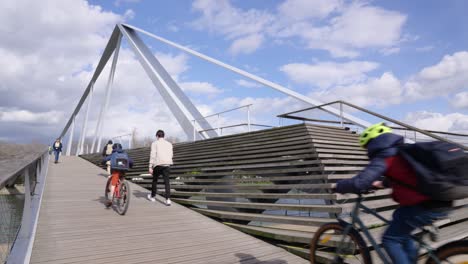 People-walking-on-wooden-deck-of-the-bridge-Passerelle-La-Belle-Liégeoise-over-River-Meuse