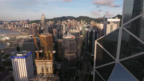 Vista-Aérea-Que-Se-Eleva-A-Lo-Largo-De-La-Torre-Del-Banco-De-China,-Con-Vistas-A-Torres-De-Oficinas-De-Gran-Altura-En-El-Soleado-Centro-De-Hong-Kong