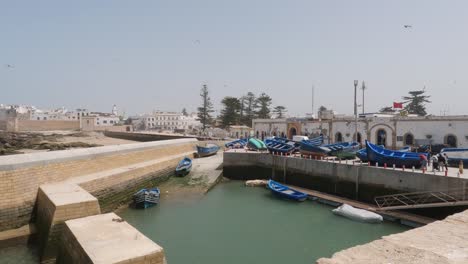 Blue-boats-waiting-for-maintenance,-waves-crashing-onto-shore