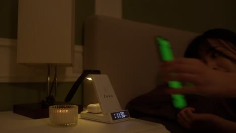 Young-girl-placing-phone-to-the-charging-station-and-turning-off-the-light