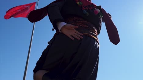 Man-in-costume-playing-zeybek-near-the-Turkish-flag-on-the-hill