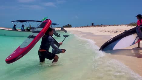 Paar-Holt-Wing-Foil-Drachen-Nach-Dem-Kitesurf-Unterricht-Aus-Dem-Meerwasser-Zum-Weißen-Sandstrand