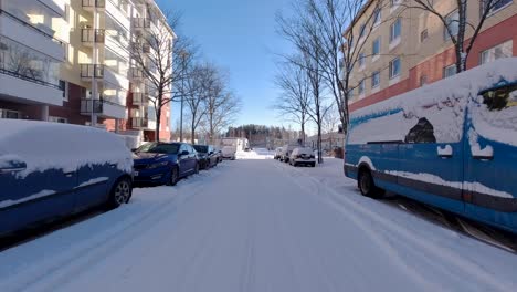 The-car-glides-through-the-winter-city,-flanked-by-snow-clad-buildings-on-either-side,-creating-a-scenic-drive