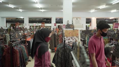 Familia-Feliz-Con-Niñas-Eligiendo-Ropa-Nueva-En-El-Centro-Comercial