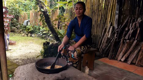 Slow-motion-medium-shot-while-an-employee-from-a-coffee-farm-stirs-and-roasts-exclusive-kopi-luwak-coffee-beans-in-a-wow-with-a-wooden-spoon-for-that-unmistakable-taste