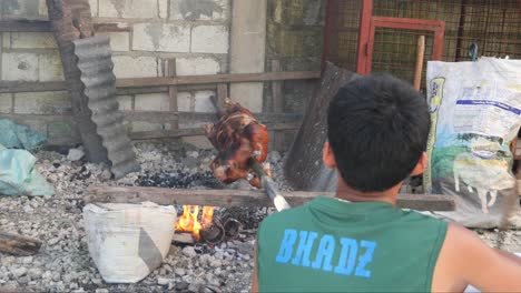 22-De-Abril-De-2023-Ciudad-De-Danao,-Cebú,-Filipinas---Un-Hombre-Está-Asando-Un-Lechón-Baboy-O-Un-Cochinillo-Con-Una-Piel-Roja-Crujiente-Sobre-Un-Fuego-De-Carbón-En-Un-Patio-Trasero-Local