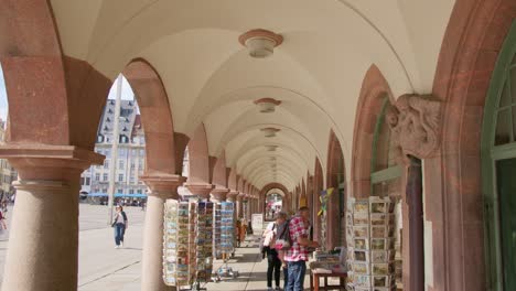 Caminando-Bajo-El-Antiguo-Ayuntamiento-Con-Tiendas-Turísticas-Junto-Al-Mercado.