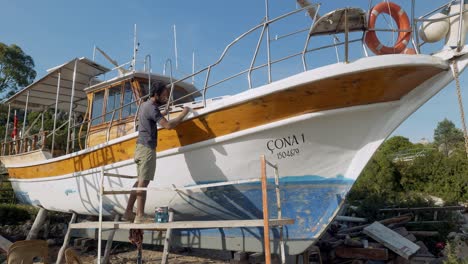 El-Hombre-Pinta-El-Casco-Del-Barco-En-El-Dique-Seco-Preparación-Para-La-Temporada-De-Turistas-De-Vacaciones