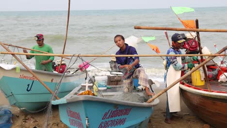 Amplia-Vista-De-Los-Pescadores-Cargando-Redes-En-Barcos-Pesqueros-De-Madera-Después-De-Vender-Capturas-En-El-Mercado-Matutino-En-La-Playa