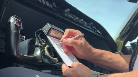 Piloto-Haciendo-Frente-A-La-Autorización-De-Control-De-Tráfico-Aéreo-En-El-Soporte-De-La-Almohadilla-Con-Un-Bolígrafo-Plateado