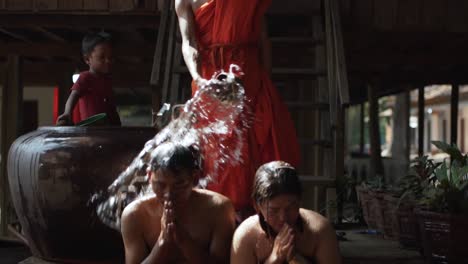 Panning-shot-of-a-buddhist-monk-performing-a-water-blessing-ritual-at-Angkor-Wat---Siem-Reap,-Cambodia