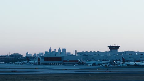 Una-Amplia-Toma-De-Taxis-De-Aviones-Comerciales-Delta-Junto-Al-Aeropuerto-Atl-Con-El-Horizonte-De-Atlanta-Georgia-Al-Fondo-Por-La-Mañana