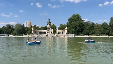 Serene-waters:-boats-gliding-across-El-Retiro-park-lake,-in-a-hot-summer-day