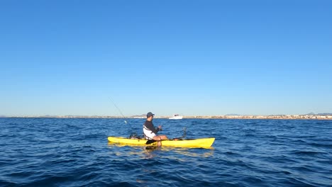 Mil-Palmeras-beach,Alicante,-Spain,-May-22,-2023:-Kayak-fishing-underwater-view-of-a-little-Fish-hooked-to-a-lure-being-pulled-outof-water-by-a-fisherman-standing-on-a-kayak-off-the-coast-of-Mil