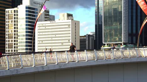 Pedestrians-walking-across-Victoria-bridge-and-buses-travelling-on-the-busway-connecting-between-central-business-district-and-South-Brisbane-at-sunset,-Queensland,-Australia,-static-shot