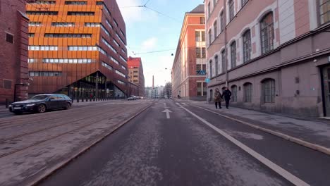 On-the-busy-street,-cars-are-driving-in-both-directions-while-pedestrians-carefully-cross-the-road-at-the-designated-pedestrian-crossing