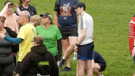 Un-Grupo-De-Corredores-Se-Reúnen-Hablando-Y-Apoyándose-Mutuamente-En-El-Campo-Del-Parque-Local-Al-Inicio-De-Su-Carrera-De-Fitness.