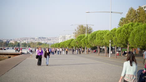 city-life-by-the-sea-People-walking-baby-stroller-electric-bikes-Thessaloniki-Beach-Promenade-sunny-summer-day