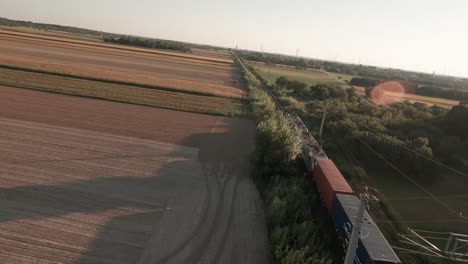 Imágenes-Cinematográficas-De-Un-Dron-De-Un-Tren-Atravesando-Un-Vasto-Campo-De-Maíz,-Bañado-Por-Los-Cálidos-Tonos-De-Una-Tarde-De-Otoño.