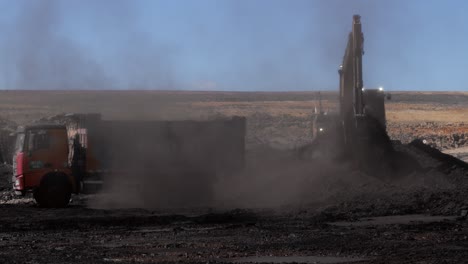 Bagger-Lädt-Zerkleinerte-Kohle-In-Muldenkipper,-Staubige-Minenumgebung