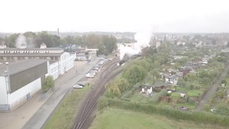 Drohnenaufnahme-Einer-Alten-Dampflokomotive,-Die-Einen-Bahnhof-Verlässt