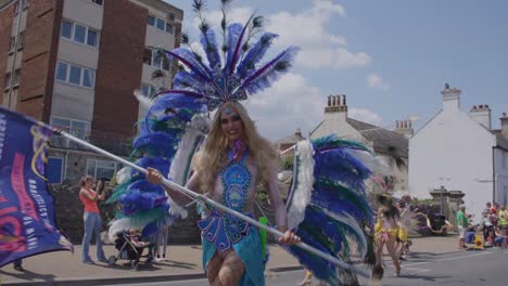 Frau-Im-Pfauenkostüm-Schwenkt-Flagge-Und-Tanzt-In-Parade-Beim-Pride-Festival-Auf-Der-Isle-Of-White-2018