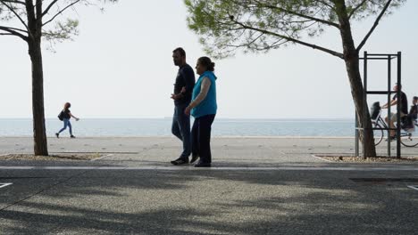 People-passing-by-Thessaloniki-Beach-Promenade-sea-background-sunny-day-summer