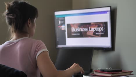 Ein-Blick-Von-Hinten-Auf-Eine-Frau,-Die-Auf-Einer-Tastatur-Tippt-Und-Auf-Einen-Monitor-Schaut