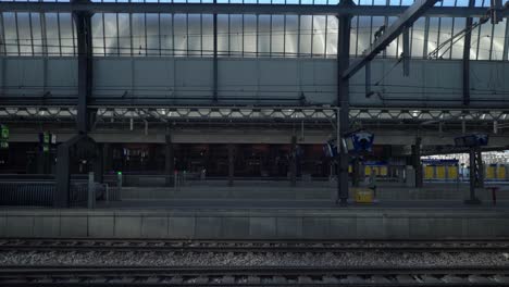 Mujer-Caminando-Sobre-Una-Plataforma-Vacía-En-La-Estación-Central-De-Tren-Durante-El-Cierre-De-Covid19,-Noord-Holland,-Amstersam,-Países-Bajos