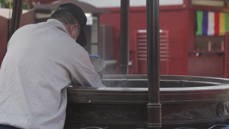 Mann-Entfernt-Asche-Aus-Weihrauchbrenner-Im-Senso-Ji-Tempel-In-Asakusa,-Tokio,-Japan