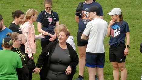 Un-Grupo-De-Corredores-Se-Reunió-Hablando-Y-Apoyándose-Mutuamente-En-El-Campo-Del-Parque-Local-Al-Inicio-De-Su-Carrera-De-Fitness.