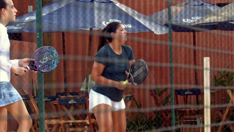 Vista-A-Través-De-La-Valla-De-La-Cancha-De-Dos-Niñas-Jugando-Tenis-De-Playa-En-Cámara-Lenta-En-Brasilia,-Brasil