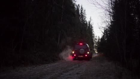 Aus-Der-Rückseite-Des-Geländewagens-Strömt-Rauch-Aus-Dem-Auspuff,-Als-Er-Bei-Sonnenuntergang-Auf-Einem-Ländlichen-Weg-Rückwärts-Fährt