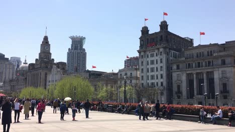 People-and-tourists-walking-in-front-of-AIA-Shanghai-Office-and-Custom-House-Building-at-Bund,-Shanghai,-China,-static-shot