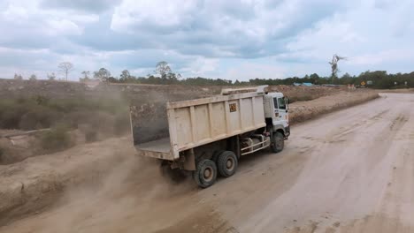 Seguimiento-Aéreo-De-Un-Camión-Volquete-Con-Caja-Abierta-Vacía-En-Un-Camino-De-Tierra-Lleno-De-Baches