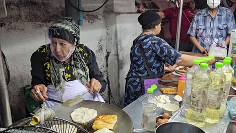 Restaurante-De-Comida-Callejera-Con-Premio-Michelin,-Anciana-Volteando-Comida-En-Una-Sartén-Caliente