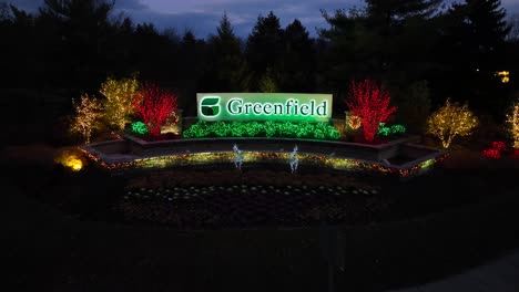 Aerial-approaching-drone-shot-of-Greenfield-sign-lighting-with-Christmas-decoration-at-street-with-driving-cars