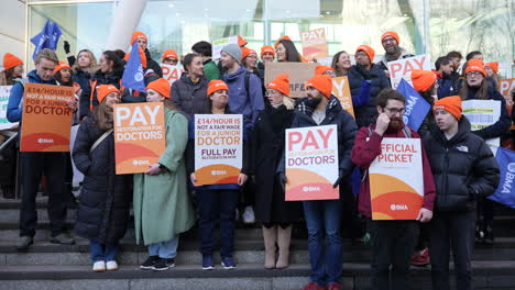 Am-26.-Streiktag-Halten-Junge-Ärzte-Mit-Orangefarbenen-Hüten-Der-British-Medical-Association-Orangefarbene-Plakate-An-Einer-Streikpostenlinie-Vor-Dem-Eingang-Des-University-College-London-Hospital