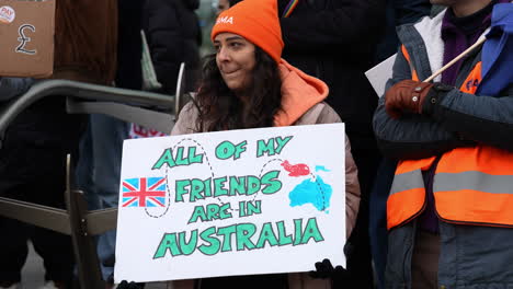 En-Cámara-Lenta,-Una-Mujer-Sostiene-Un-Cartel-De-Cartón-Que-Dice:-&quot;Todos-Mis-Amigos-Están-En-Australia&quot;-En-Un-Piquete-De-Huelga-Frente-A-La-Entrada-Del-Hospital-University-College-De-Londres.