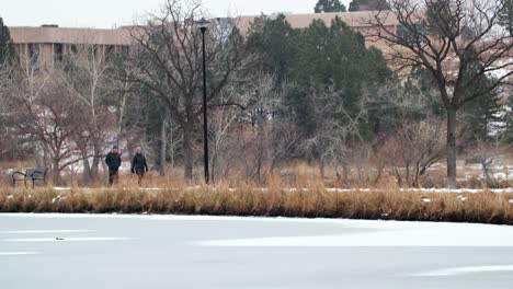 Pareja-Caminando-Por-El-Sendero-En-El-Parque-Con-Lago-Congelado-En-Colorado